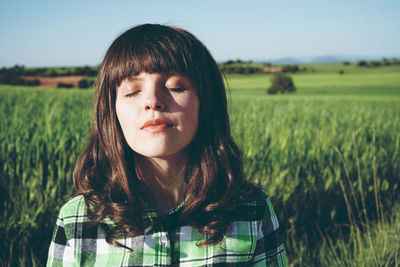 Woman with eyes closed standing on field during sunny day