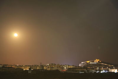 Illuminated buildings in city against sky at night