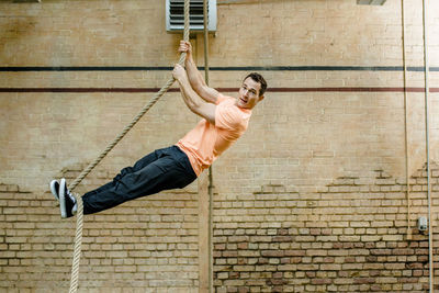 Full length of young man hanging against brick wall