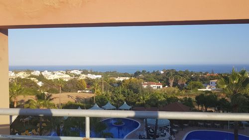 Plants by swimming pool against sea against clear sky