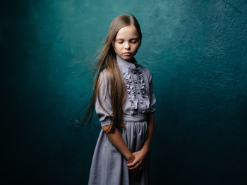 Portrait of teenage girl standing against blue wall