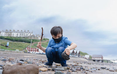 Full length of boy sitting against sky