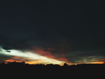 Silhouette landscape against dramatic sky during sunset