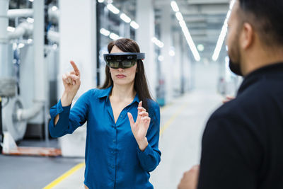 Businesswoman with augmented reality glasses explaining to engineer in industry