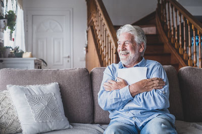 Midsection of man sitting on sofa at home