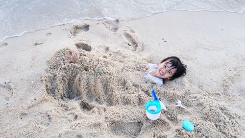 High angle view of girl lying on sand at beach