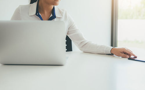 Midsection of woman using laptop on table