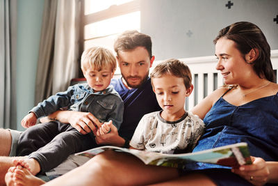 Parents and kids sitting on bed at home