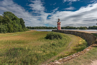 Lighthouse on field against sky