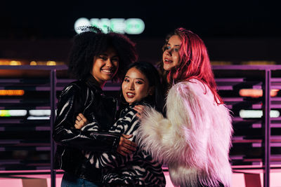 Portrait of smiling women standing outdoors at night