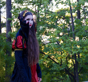 Portrait of teenage girl wearing halloween costume while standing against trees