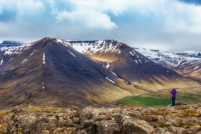 Rear view of person on snowcapped mountain against sky