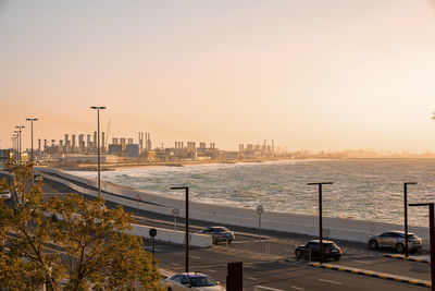 Scenic view of coastal road beside beach against romantic sky