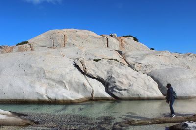 Man standing by rock formation at beach in la maddalena
