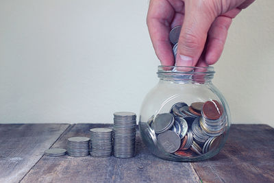 Close-up of hand holding glass jar on table