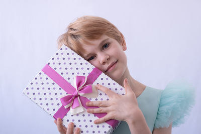 Portrait of woman holding gift against white background