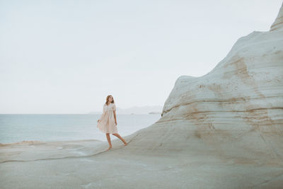 Woman standing on beach against clear sky