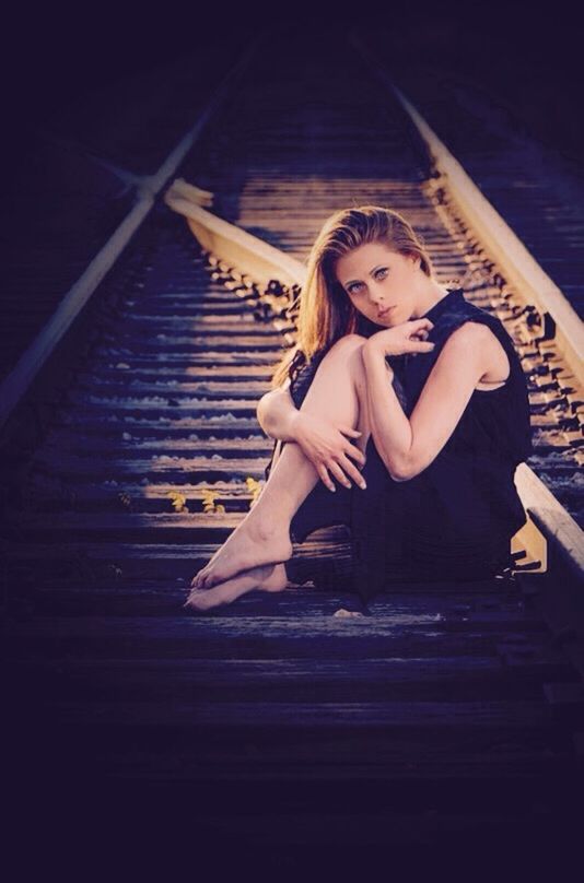 PORTRAIT OF YOUNG WOMAN SITTING ON WALL