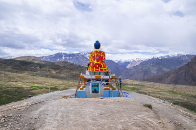 Rear view of cross on landscape against sky