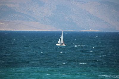 Sailboat sailing on sea against blue sky