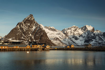 Scenic view of lake by snowcapped mountains against sky