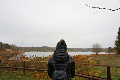 Rear view of man looking at railing against sky