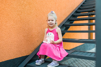 Portrait of cute girl standing against wall