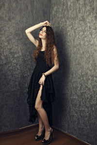 Young woman standing on floor against wall