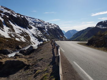 Scenic view of road by mountains against sky