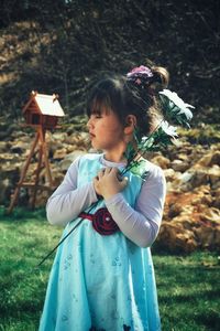 Cute girl with flower standing in lawn