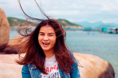 Portrait of smiling woman against sea