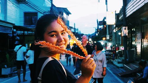 Portrait of woman eating food in city