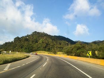 Road by trees against sky