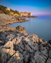 Rocks on beach by sea against sky