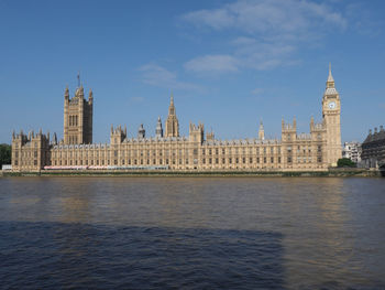 Buildings by river against sky