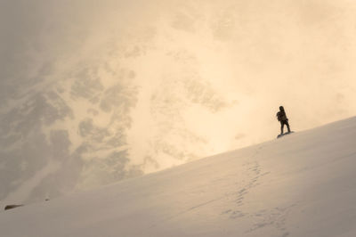 Silhouette person on snowcapped mountain against sky