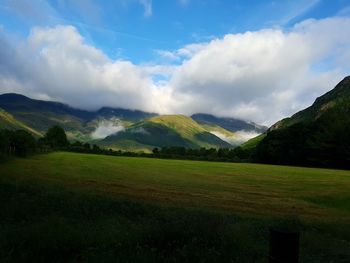 Scenic view of grassy field against cloudy sky