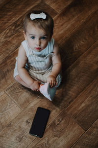 High angle view portrait of cute girl using laptop on hardwood floor