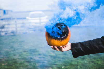 Close-up of person holding ice cream against sky
