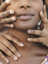 Hands touching face of young woman