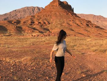 Rear view of woman standing on rock against sky