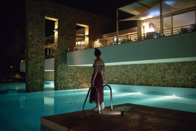 Rear view of woman standing against illuminated building