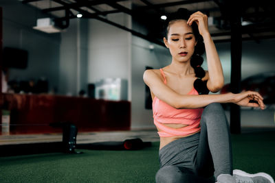 Young woman looking away while sitting on floor