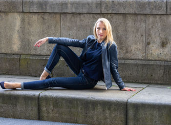 Portrait of young woman standing against wall