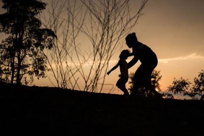 Silhouette man standing on field against sky during sunset