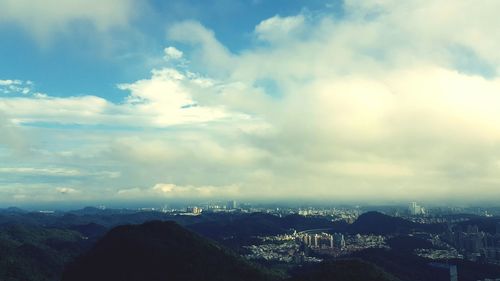 Aerial view of cityscape against cloudy sky