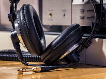 Black hi-fi headphones with a gold input jack on a wooden floor