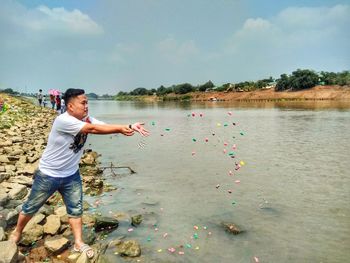 Man standing in lake against sky