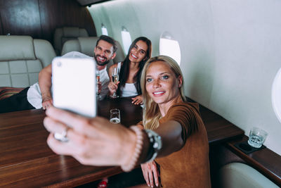 Friends taking selfie on phone in airplane