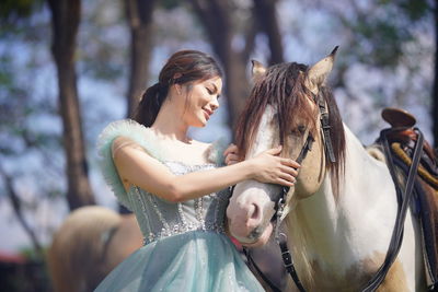 Side view of woman with horse in park